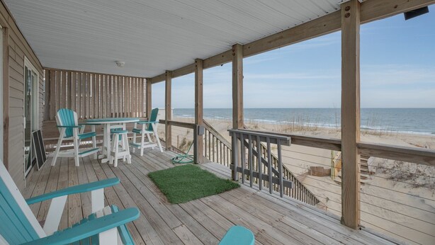 A wooden deck with a view of the beach, outdoor seating, and a small staircase leading to the beach. - 5061 - Good Night Irene - Oceanfront Cottage w/ Decks & Stunning Views (Kill Devil Hills)