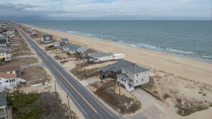 A coastal road with houses on one side and the beach on the other. - 5061 - Good Night Irene - Oceanfront Cottage w/ Decks & Stunning Views (Kill Devil Hills)