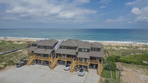 Een hotel aan het strand met meerdere gebouwen, een parkeerplaats en uitzicht op het strand.