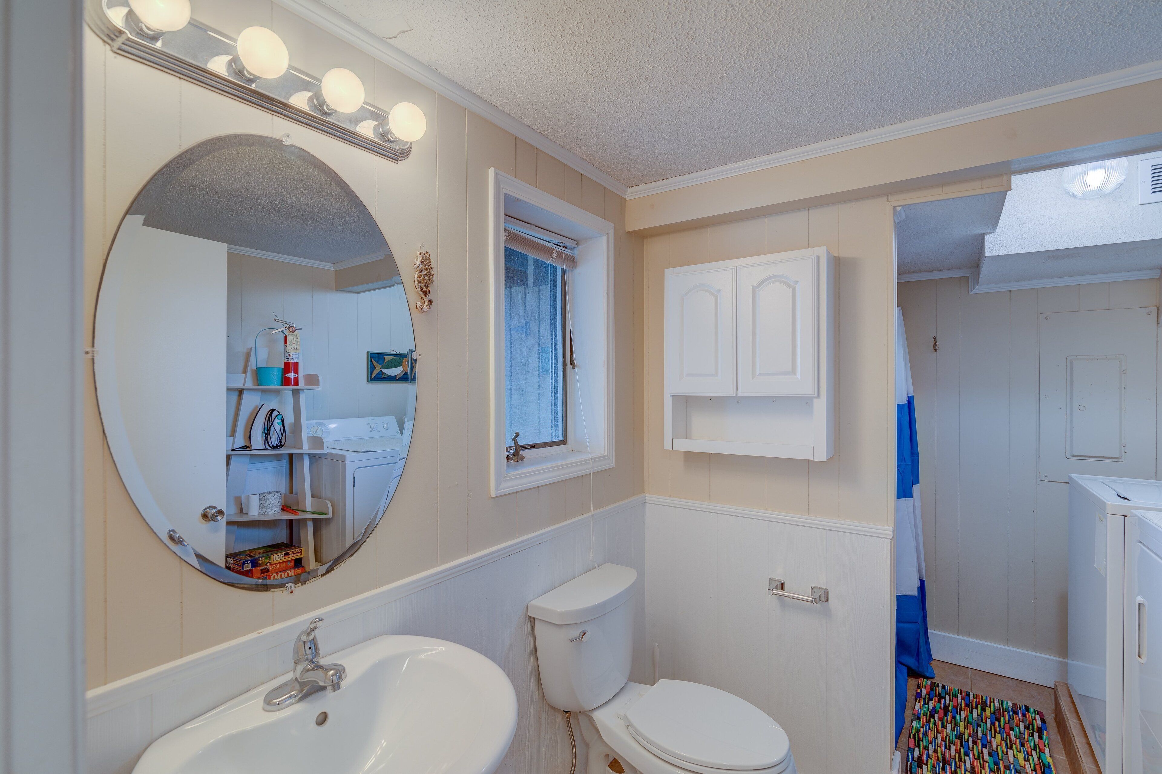 A bathroom with a large mirror, a sink, a toilet, and a cabinet.