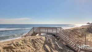 Eine Holztreppe führt zu einem Strand mit freiem Blick auf den Ozean.