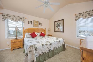 A bedroom with a bed, nightstands, a ceiling fan, and a window with blinds.