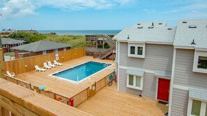 A two-story building with a wooden deck and a swimming pool.