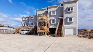 A multi-story residential building with a garage, wooden staircases, and a white van parked in front.