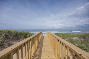 Una pasarela de madera que conduce a la playa, con vistas al océano.