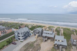 Zona residencial costeira com casas, praia e vista clara do oceano.