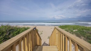Une promenade en bois menant à une plage avec vue sur l’océan.