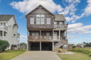 A two-story wooden house with a balcony, a garage, and a clear sky.