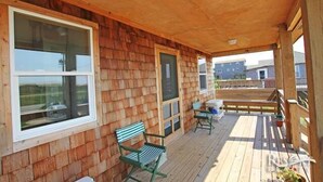 A wooden deck with a covered porch, wooden walls, and a view of a residential area. - 5443- Gillam Cottage, Oceanfront | Nags Head | Sleeps 8 (Nags Head)