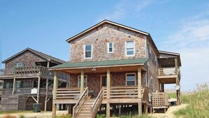 A wooden house with a porch and a small deck. - 5443- Gillam Cottage, Oceanfront | Nags Head | Sleeps 8 (Nags Head)