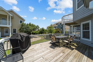 A wooden deck with a covered grill, outdoor table and chairs, and a white fence. - 5598-Serenity - Dog-Friendly Nags Head Duplex Retreat (Nags Head)