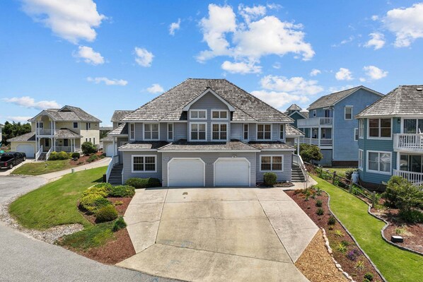 A two-story house with a front driveway, two garages, and a well-maintained lawn. - 5598-Serenity - Dog-Friendly Nags Head Duplex Retreat (Nags Head)