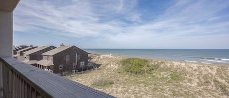 Vista de una playa con una terraza de madera y un edificio de varios pisos.