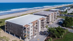 Un hotel a più piani con tetto piatto, situato vicino a una spiaggia, con parcheggio e vista sull'oceano.