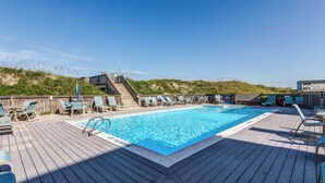 Una terraza de madera con piscina, sillas de descanso y una escalera que sube a un nivel superior.