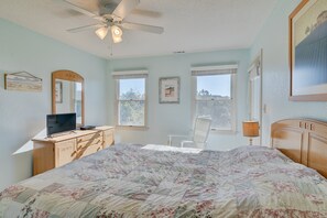 A bedroom with a bed, a desk, a chair, a ceiling fan, and two windows. - 5647- Sandy Pause - Nags Head Escape | Beach Club & Pool Access (Nags Head)