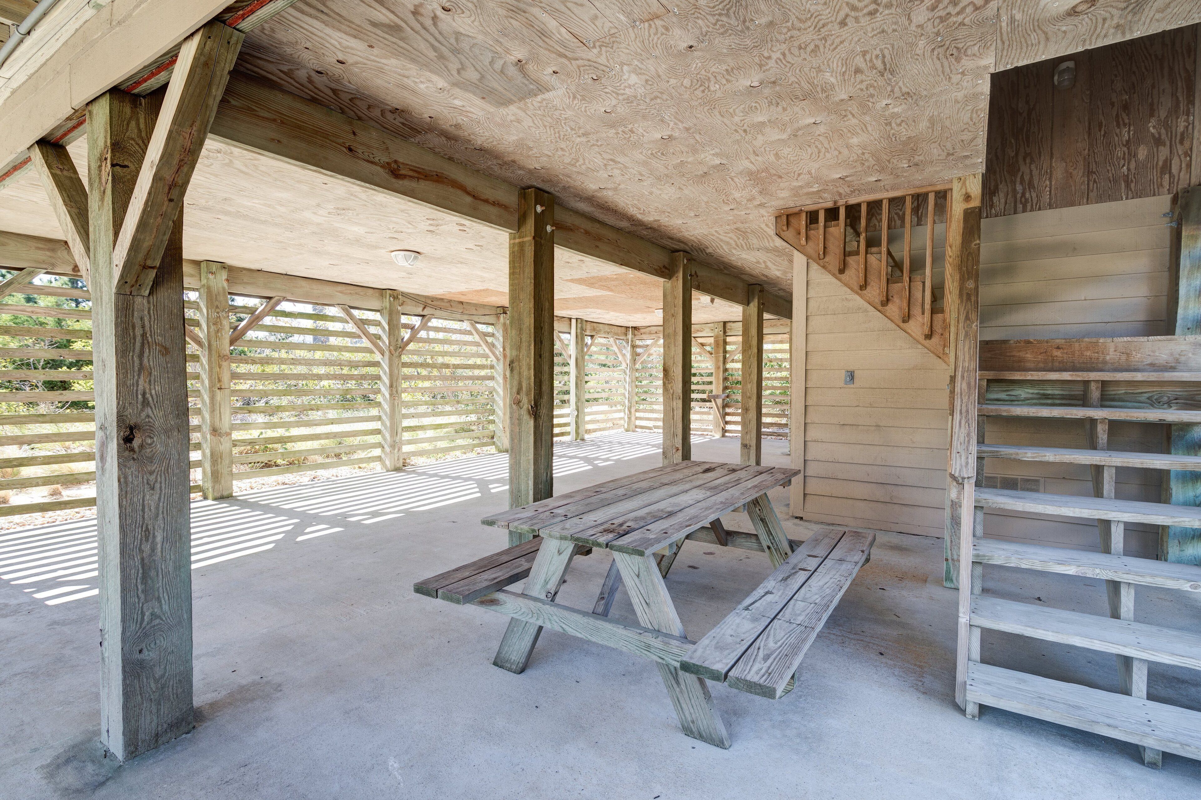 A covered outdoor area with a picnic table and wooden benches.