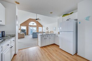 A modern kitchen with white cabinetry, a built-in refrigerator, and a wooden ceiling.