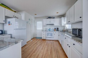 A kitchen with white cabinets, a refrigerator, a stove, a microwave, and a sink.