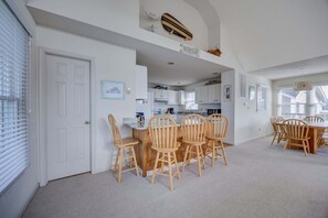 A spacious dining area with a high ceiling and a view of the kitchen.