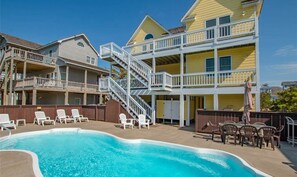 A two-story building with a swimming pool, outdoor seating, and a staircase leading to the upper level.