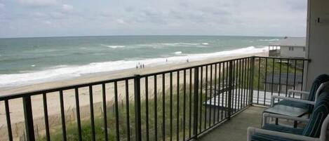 A balcony with a view of the beach and ocean.
