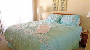 Una cama con una colcha estampada, una lámpara de noche y una mesita de noche con un teléfono.