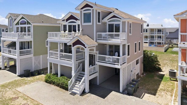 A multi-story hotel with balconies, a central staircase, and a beach view. - 5702- It's A Wonderful Life, Steps to Beach | Pool, Hot Tub & Game Room (Nags Head)