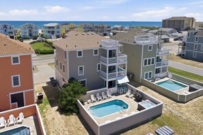 Et hotel ved stranden med flere bygninger, en swimmingpool og udsigt over havet.