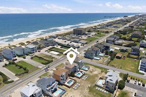 Vista aérea de una zona residencial costera con casas, una playa y un muelle.