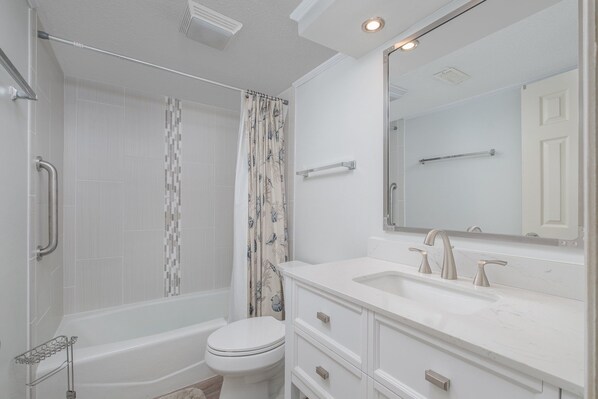 Un bagno moderno con vasca, servizi igienici e un mobile lavabo con lavandino e specchio.