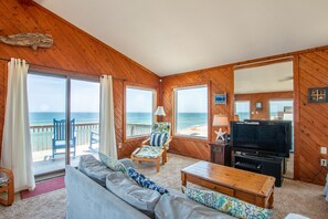 Enjoy the ocean view from the comfort of this living room, featuring a sofa, coffee table, and television.