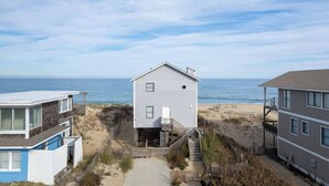 A beachfront house with a staircase leading to the beach, a sandy path, and a view of the ocean. - 5782-Whale of a View - Charming Oceanfront Nags Head Cottage (Nags Head)