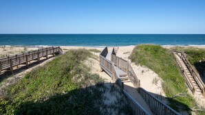 A beach with wooden boardwalks leading to the ocean. - 5786- After All - Oceanfront South Nags Head w/ Elevator (Nags Head)