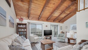 A cozy living room with a wooden ceiling, a sofa set, a television, and a bookshelf. - 5793- Beachy Keen - South Nags Head Retreat Steps From Beach (Nags Head)