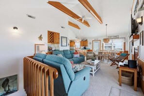 En rummelig opholdsstue med en sofa, et spisebord og et køkken i baggrunden.