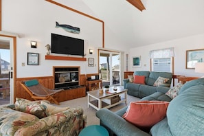 A cozy living room with a fireplace, a television, and a balcony with a view.