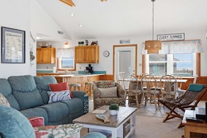 A cozy living room with a sofa, chairs, a coffee table, and a dining area with a table and chairs.