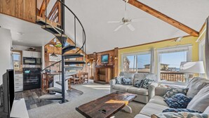 A spacious living area with a spiral staircase, a kitchen, and a seating area with a view of the beach. - 7026- Southwind - Rodanthe Cottage | 100 Yards to Beach (Rodanthe)