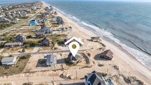 An aerial view of a coastal residential area with houses, a beach, and a marked location. - 7026- Southwind - Rodanthe Cottage | 100 Yards to Beach (Rodanthe)