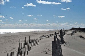 Een zandstrand met een houten omheining en een heldere lucht.