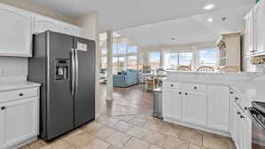 Eine moderne Küche mit weißen Schränken, einem Edelstahlkühlschrank und einem Essbereich mit Blick.
