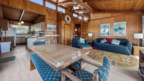 L’intérieur d’un chalet en bois comprend une table à manger, des chaises rembourrées bleues, un canapé et un coin cuisine.