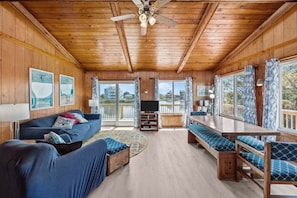 A wooden cabin interior with a sofa, TV, dining table, and chairs. - 7555-Saucy Lido, Canalfront Avon | Pool Access & Quiet Retreat (Avon)