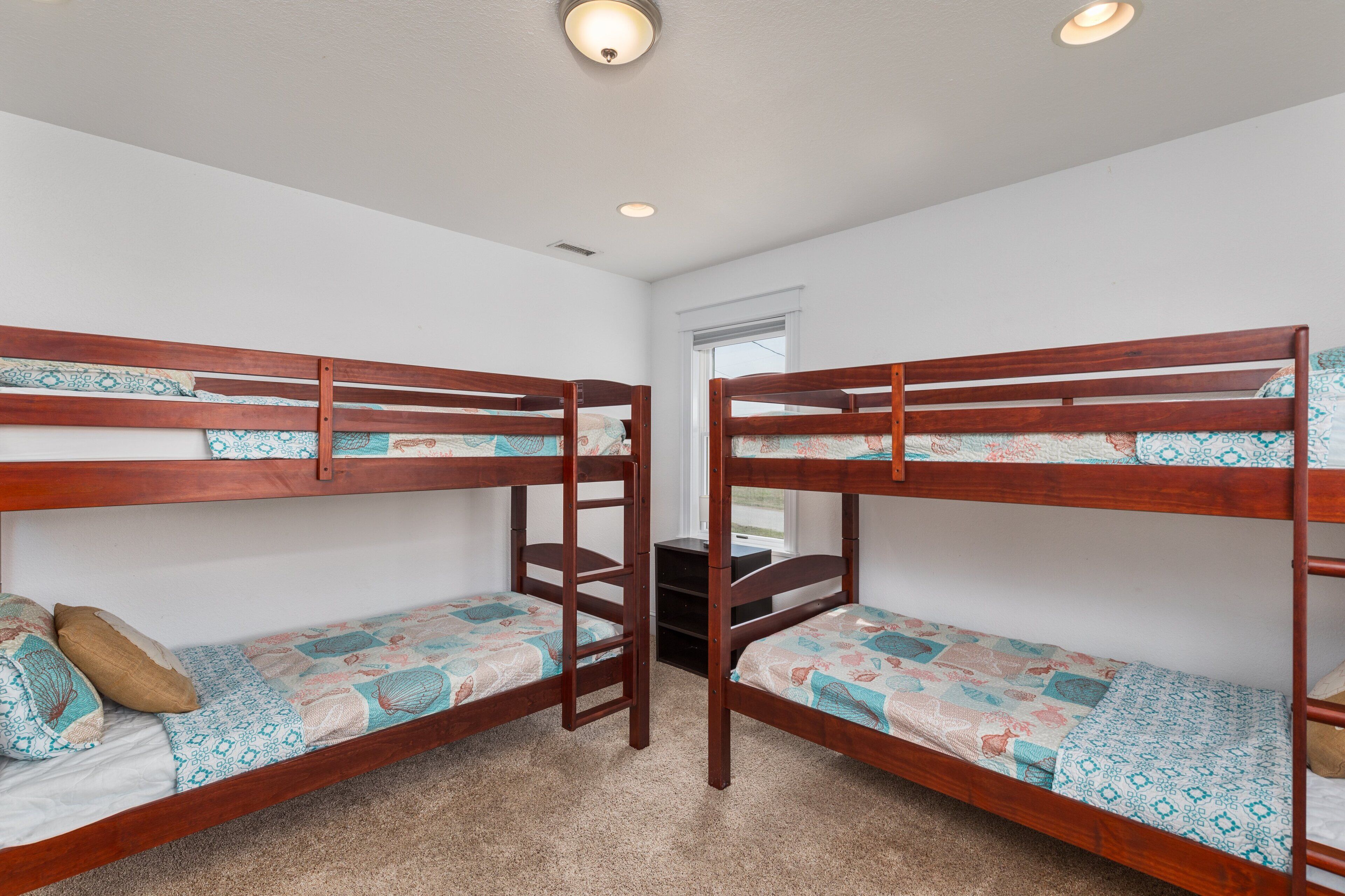 A room with two bunk beds, a small desk, and a window.
