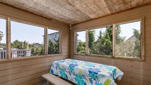 A room with a bed, a bench, and large windows offering views of houses and trees. - 7563- Sea Dreams, 200 Yards to Beach | Pool Access in Avon (Avon)