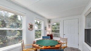 A room with a green felt game table, wooden chairs, and a white door. - 7563- Sea Dreams, 200 Yards to Beach | Pool Access in Avon (Avon)