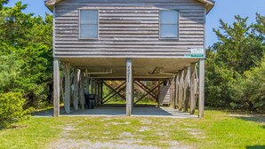 Un bâtiment en bois doté d’un porche couvert, d’une enseigne indiquant « Réservations de locations de vacances ici ! » et d’un numéro de téléphone.