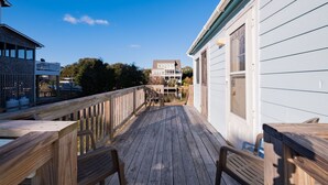 Eine Holzterrasse mit Blick auf ein Haus und einen Steg.