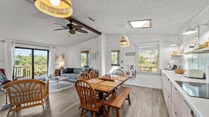A spacious dining area with a wooden table and chairs, a ceiling fan, and large windows offering a view of the outdoors. - 7850- Nepenthe - Charming Frisco Getaway Near The Beach (Frisco)